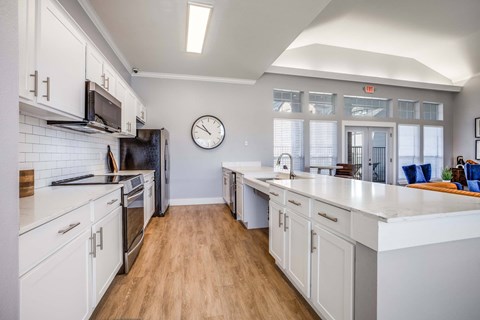 A kitchen with white cabinets and a wooden floor.