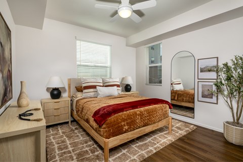 A bedroom with a bed, nightstand, and a plant.