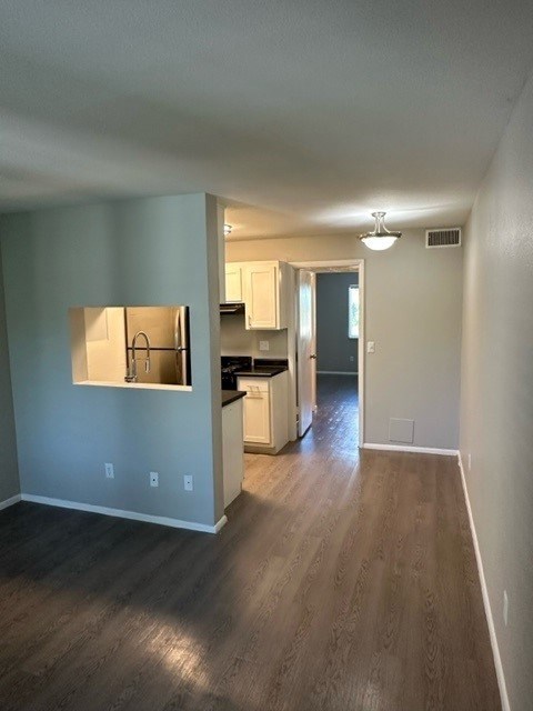 A kitchen with a sink and cabinets is visible through a window.