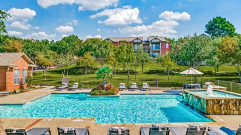 A large swimming pool surrounded by lounge chairs and trees.