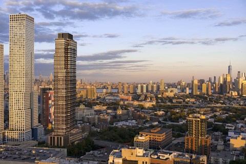 A cityscape with tall buildings and a cloudy sky.