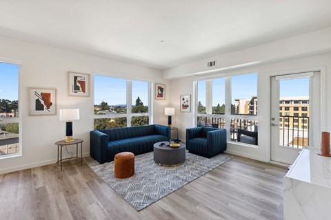 A living room with a blue couch and a grey ottoman.