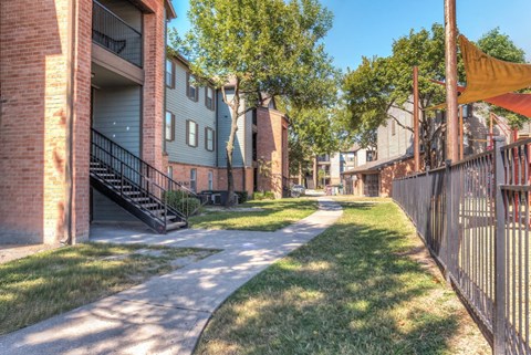 A sunny day in a residential area with apartment buildings and a pathway.