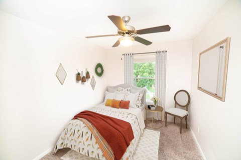 A bedroom with a bed, chair, and a window.