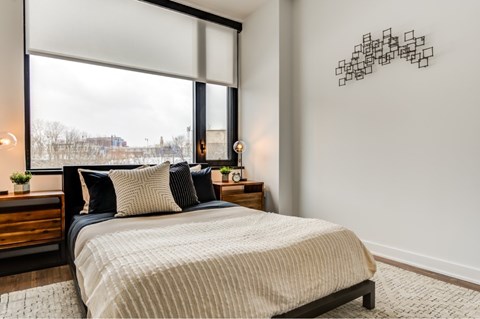 A bedroom with a large bed and a window overlooking a snowy landscape.