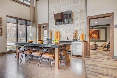 A kitchen with a table and chairs in front of a stone wall.