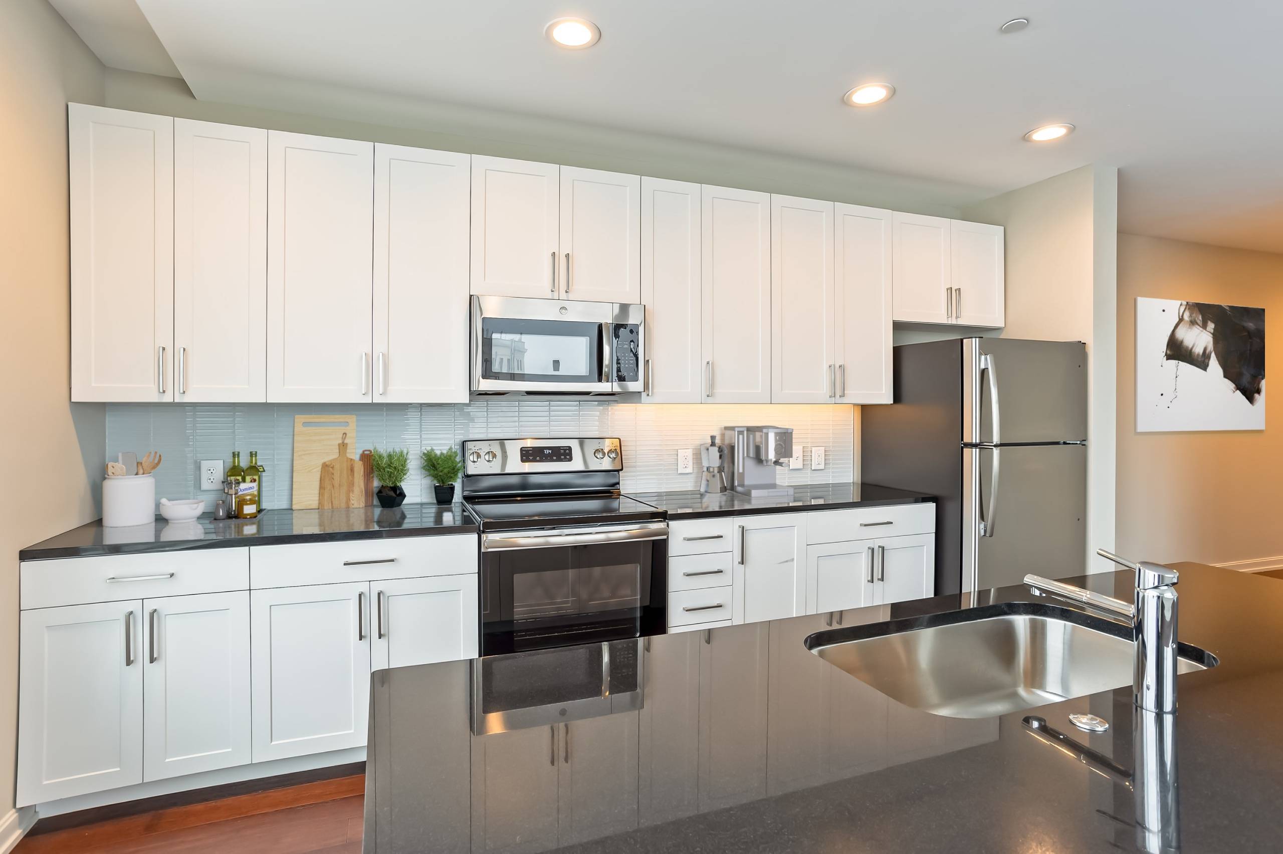 A modern kitchen with white cabinets and stainless steel appliances.