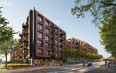 A modern red brick building with balconies and a street in front.