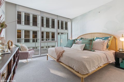 A bedroom with a large bed and a chair.