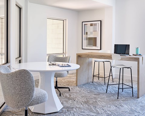 A modern dining room with a white table and grey chairs.