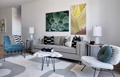 A living room with a grey couch, a blue chair, and a painting on the wall.