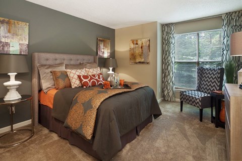 A bedroom with a large bed and a chair.