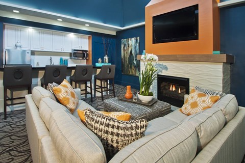 A living room with a grey couch and a fireplace.