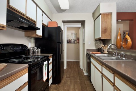 A kitchen with a black stove top oven and black refrigerator.