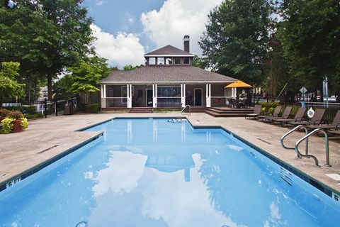 A pool in a backyard with a house in the background.