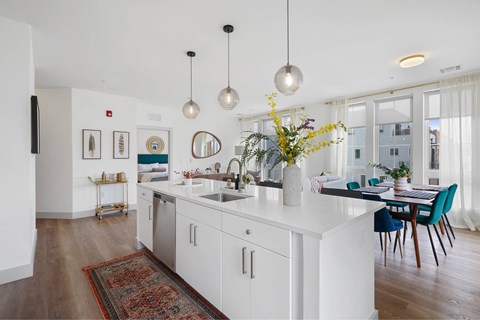 A modern kitchen with white cabinets and a wooden floor.