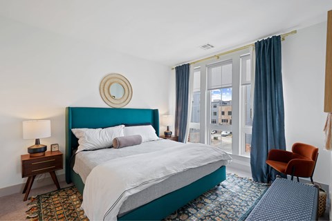 A bedroom with a large bed and a chair.