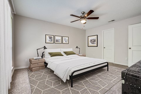 A bedroom with a large bed and a ceiling fan.