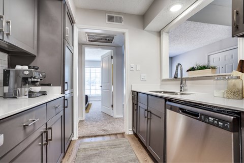 A modern kitchen with a stainless steel dishwasher and a white countertop.