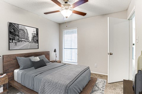 A bedroom with a bed, a ceiling fan, and a picture on the wall.