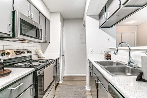 A kitchen with a stove top oven, microwave, and a sink.