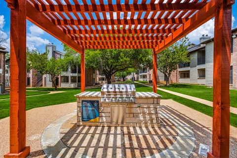 A playground with a red pergola and a slide.