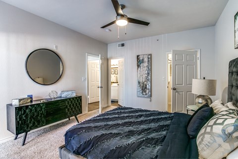 A bedroom with a large bed and a ceiling fan.