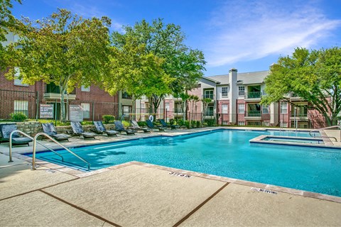 A large swimming pool surrounded by lounge chairs and trees.