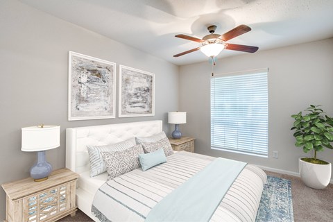 A bedroom with a bed, nightstands, and a ceiling fan.