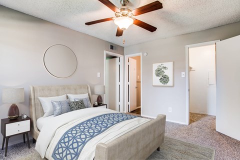 A bedroom with a large bed and a ceiling fan.