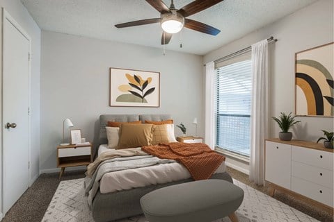 A bedroom with a bed, a ceiling fan, and a painting on the wall.