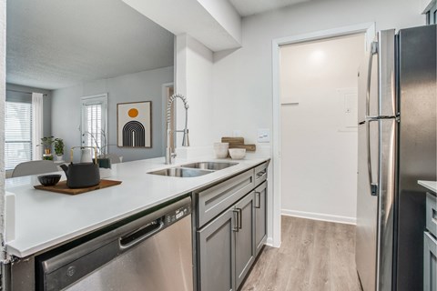 A modern kitchen with a stainless steel refrigerator and a wooden cutting board on the counter.