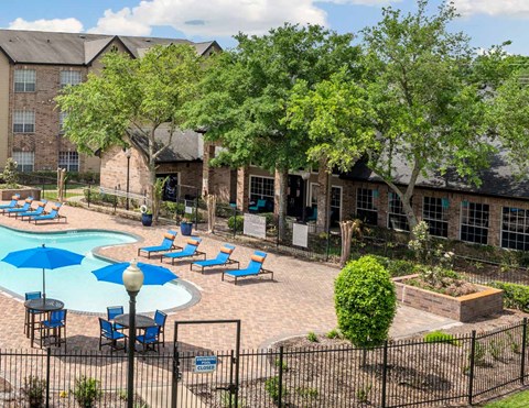 A pool surrounded by chairs and trees in a courtyard.