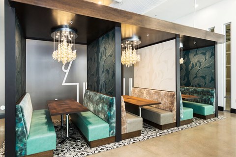 A modern dining area with a wooden table and green upholstered chairs.