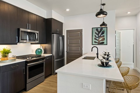 A modern kitchen with dark brown cabinets and a white island.