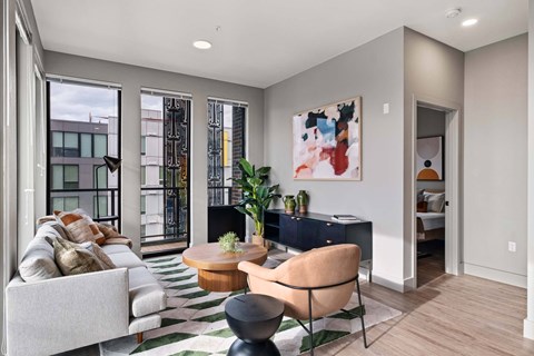 A modern living room with a large painting on the wall and a striped rug on the floor.