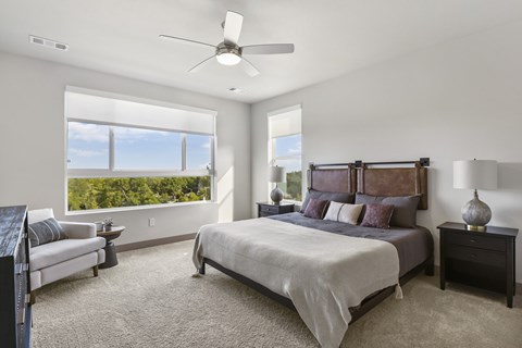 A bedroom with a large bed and a ceiling fan at Parkside at Littleton Village Littleton, Colorado apartment rentals.
