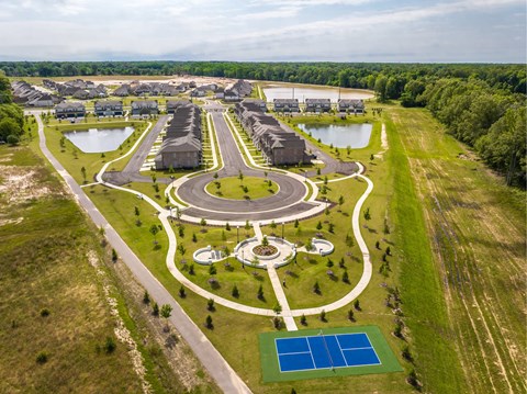 A large, well-maintained outdoor recreational area with a playground, tennis courts, and a pond.