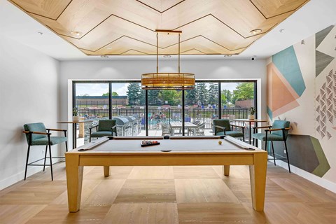A room with a long table and chairs and a pool table in the middle.