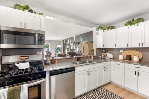 A modern kitchen with white cabinets and a black stove top.