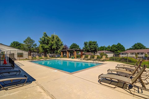 A large pool surrounded by lounge chairs and trees at Ridgeview Place Colorado Springs apartments.
