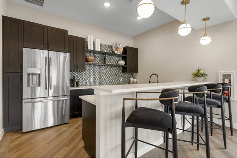 A kitchen with a stainless steel refrigerator and dark brown cabinets.