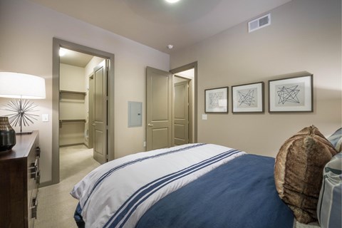 A bedroom with a bed, a lamp, and pictures on the wall.
