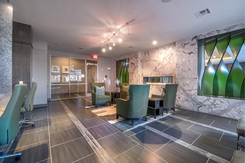 A spacious waiting area with green chairs and a marble wall.