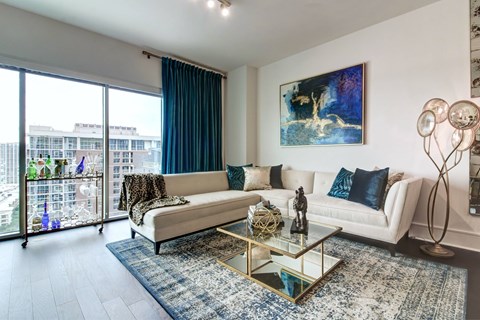 A living room with a white couch and a painting on the wall.