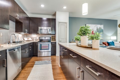 A modern kitchen with dark wood cabinets and stainless steel appliances.