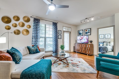 A living room with a white couch, a blue chair, and a rug with a pattern.
