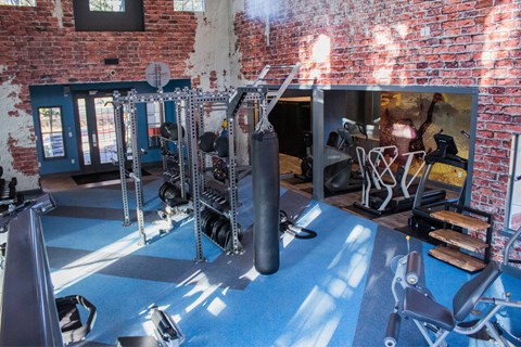 A gym with a blue floor and red brick walls.