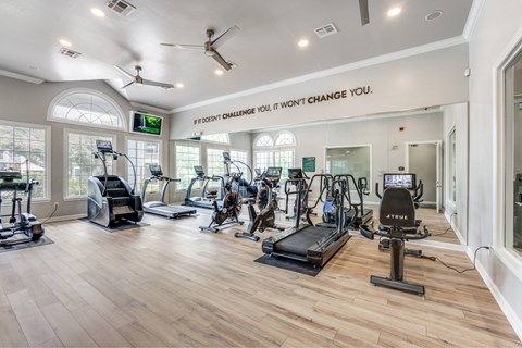 A gym with a variety of equipment and a motivational quote on the wall.