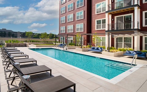 A pool with lounge chairs and a building in the background.